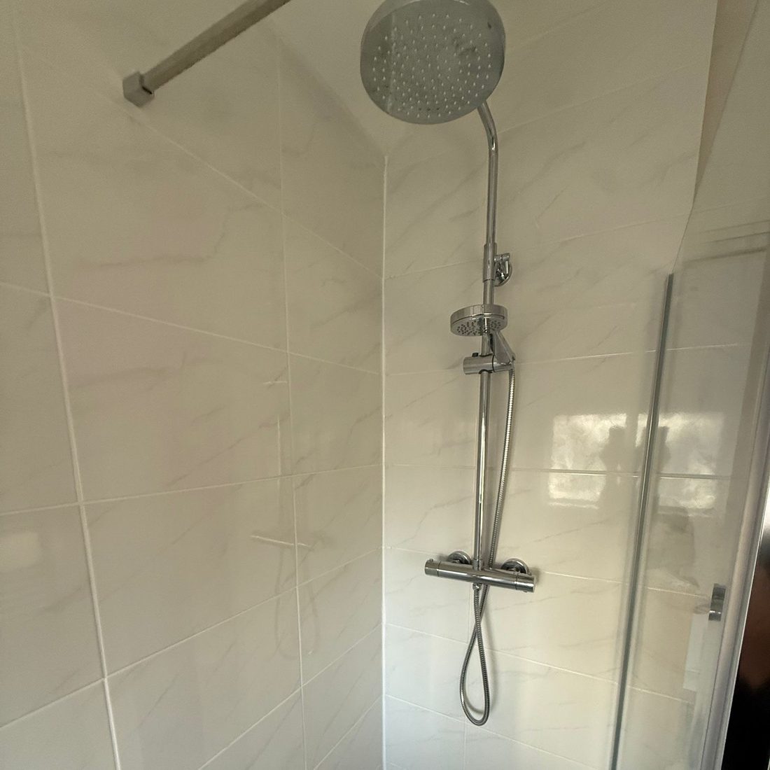 Thermostatic shower mixer fitted in a fully tiled enclosure