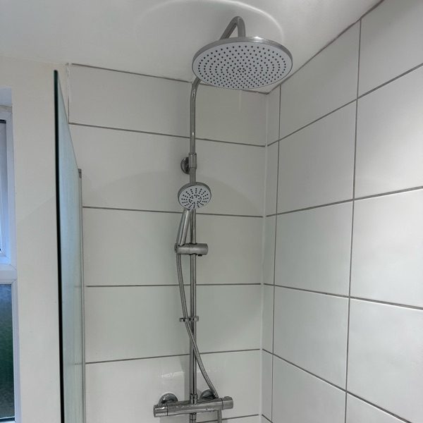 Rainfall shower head and riser fitted in a tiled cubicle