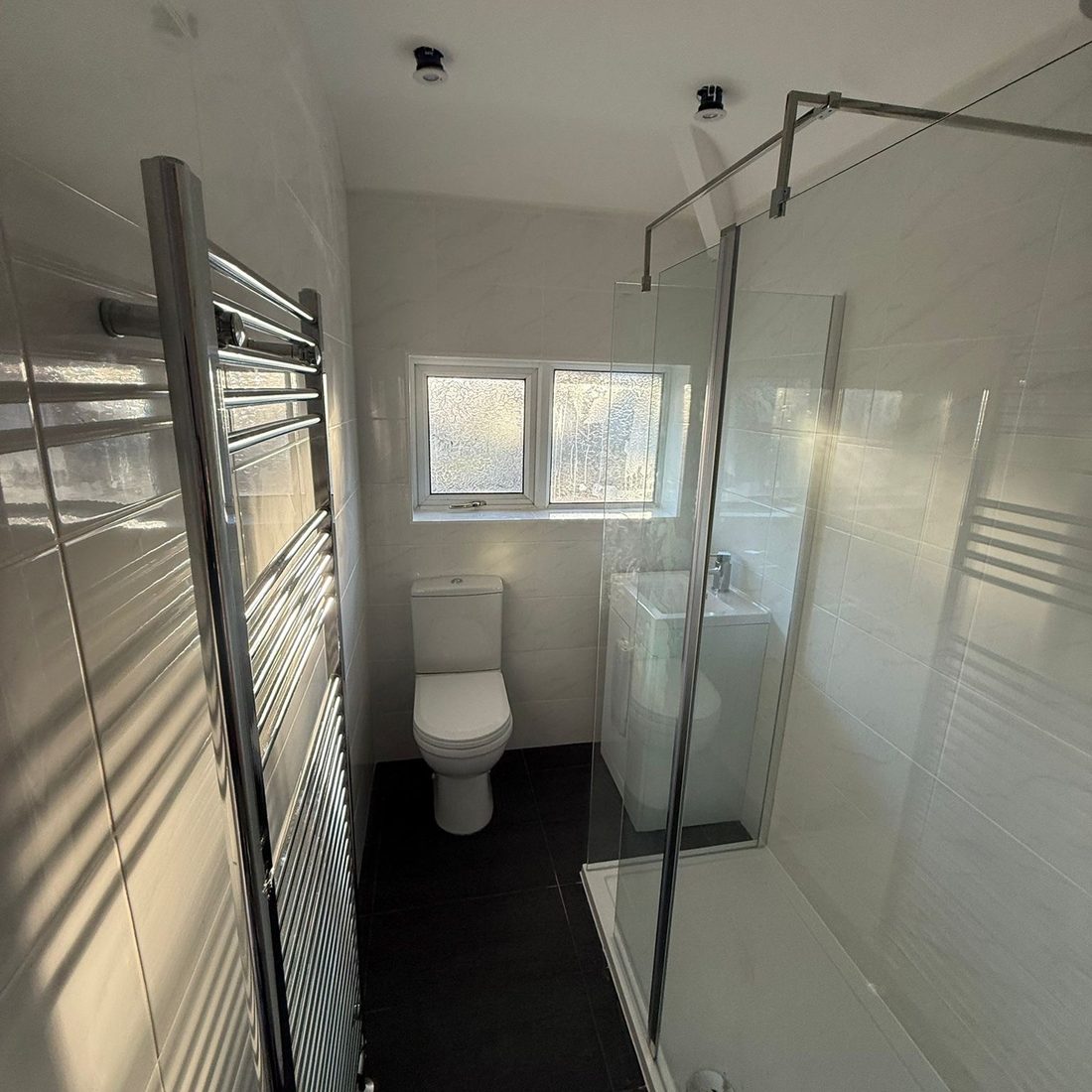 Walk-in shower enclosure and heated towel rail in a newly fitted shower room