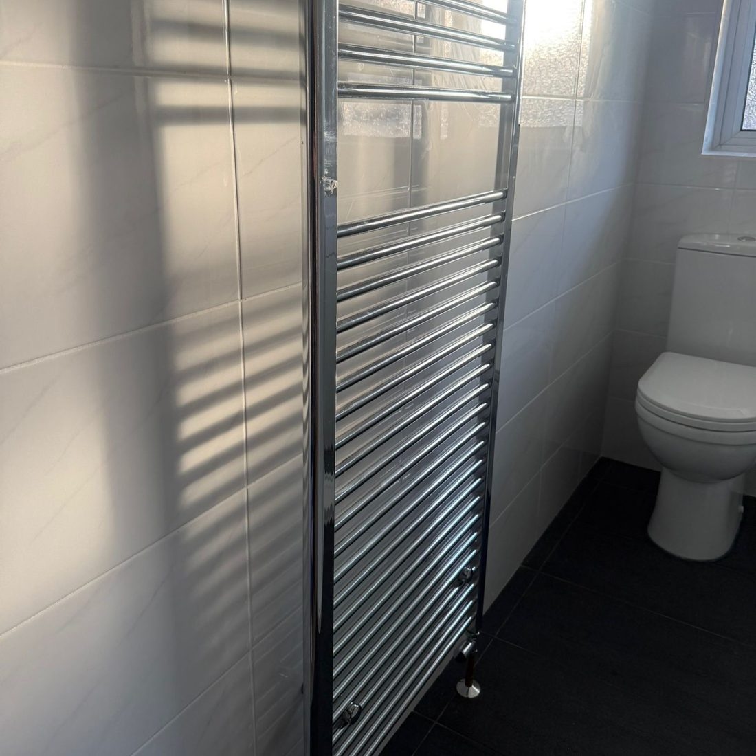 Chrome heated towel rail and shower screen in a completed shower room